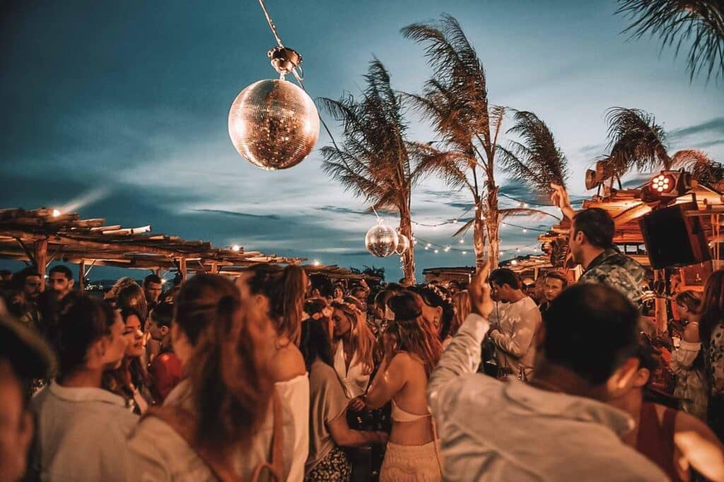 Guests gathered beneath a disco ball at Scorpios Mykonos at dusk