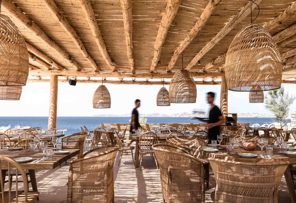 Open-air restaurant with woven chairs and sea views at Scorpios Mykonos
